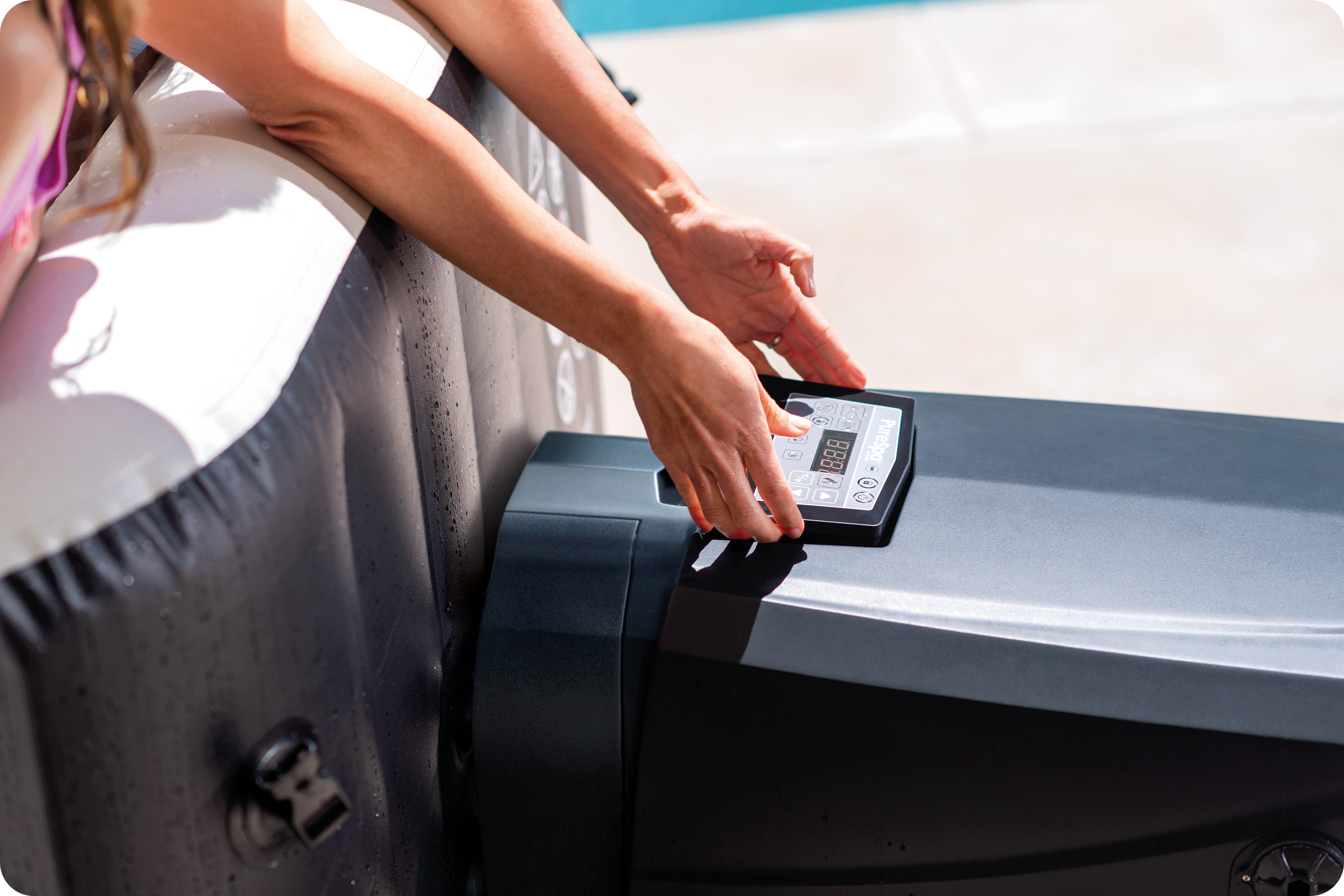 Ręce regulujące panel sterowania wanny z hydromasażem. Wanna jest czarno-biała. Tłem jest basen.