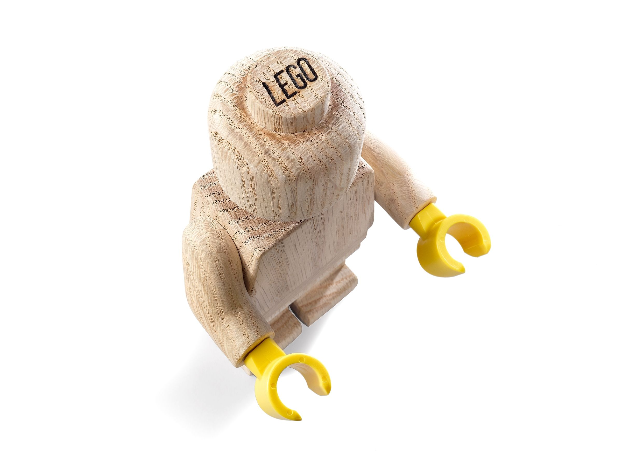 Un omino Lego di legno con mani gialle. La testa ha il logo Lego. Lo sfondo è bianco.