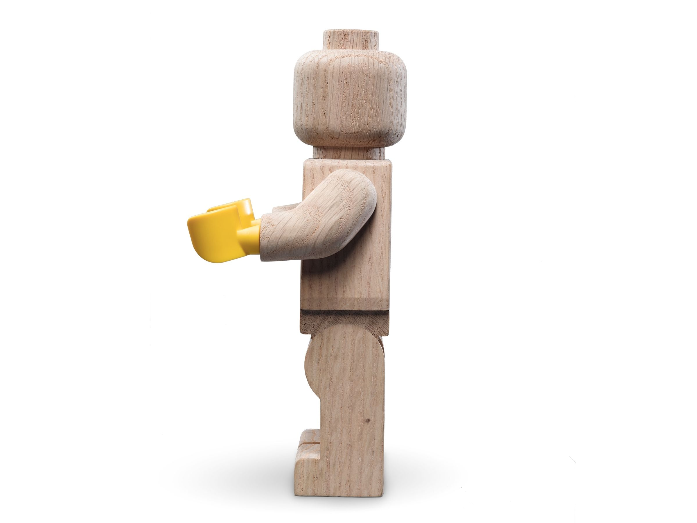 Omino Lego in legno con mano gialla. La figura è marrone chiaro, con sfondo chiaro.