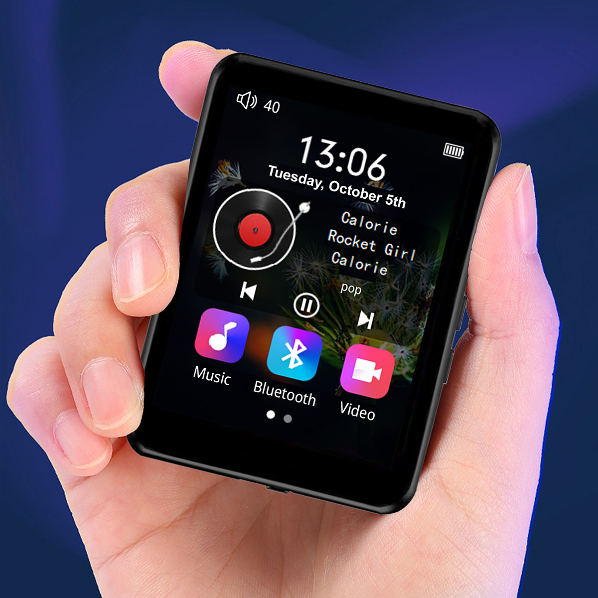 Dłoń trzymająca czarny odtwarzacz MP3. Ekran wyświetla czas, informacje o muzyce i ikony sterowania. Tło jest niebieskie.