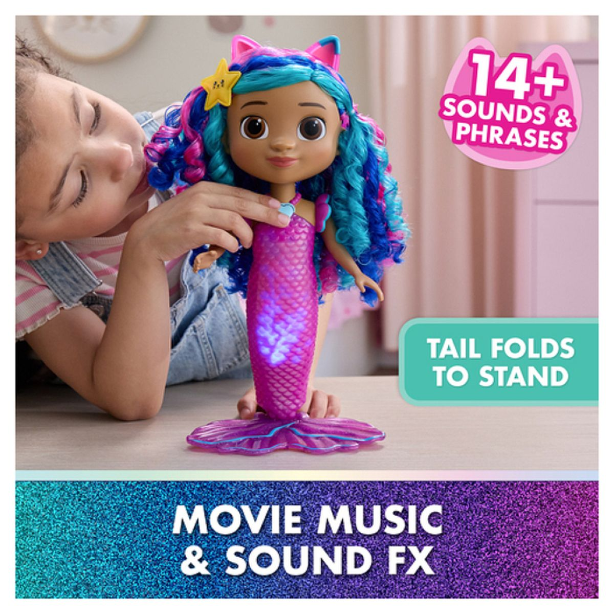 Ein Mädchen hält eine Meerjungfrauenpuppe mit blau-rosa Haaren. Die Puppe hat einen leuchtenden Schwanz und ein Katzenohren-Stirnband. Text: '14+ Sounds'.