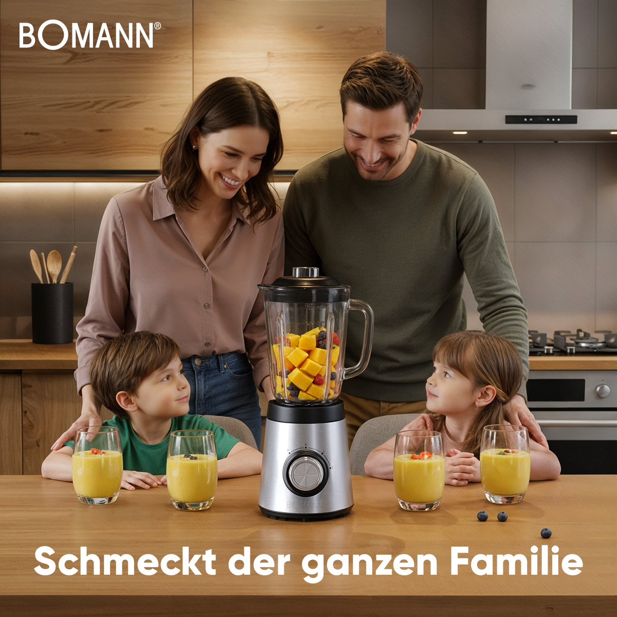 Eine Familie lächelt um einen Mixer mit Obst. Vier Gläser Saft und Blaubeeren stehen auf dem Tisch.