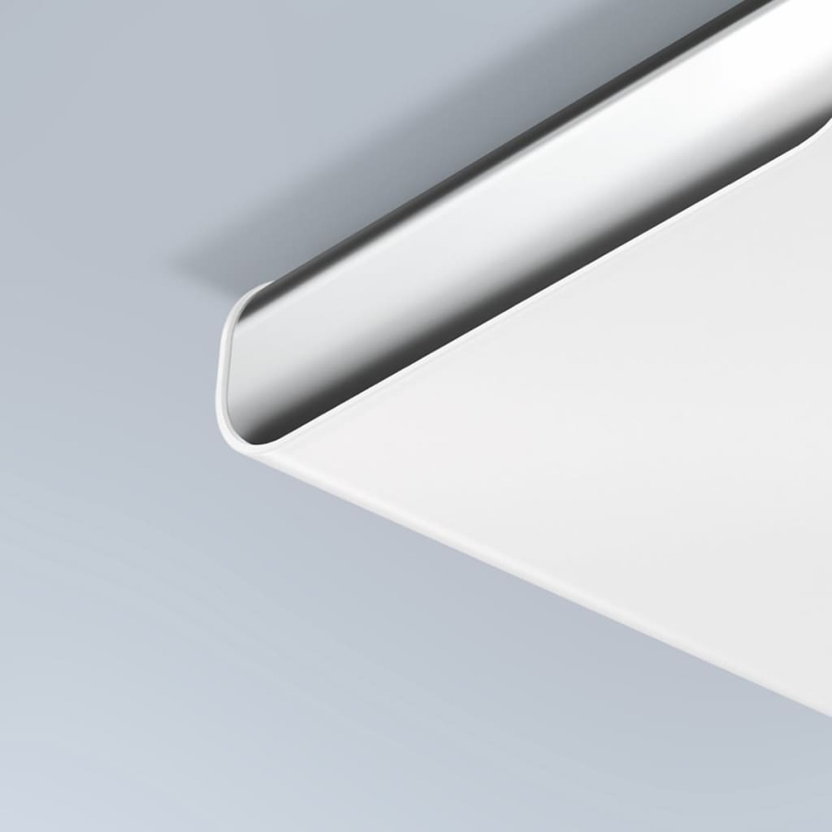 Gros plan d'un objet blanc et incurvé sur fond bleu clair. L'objet a une surface lisse et réfléchissante.