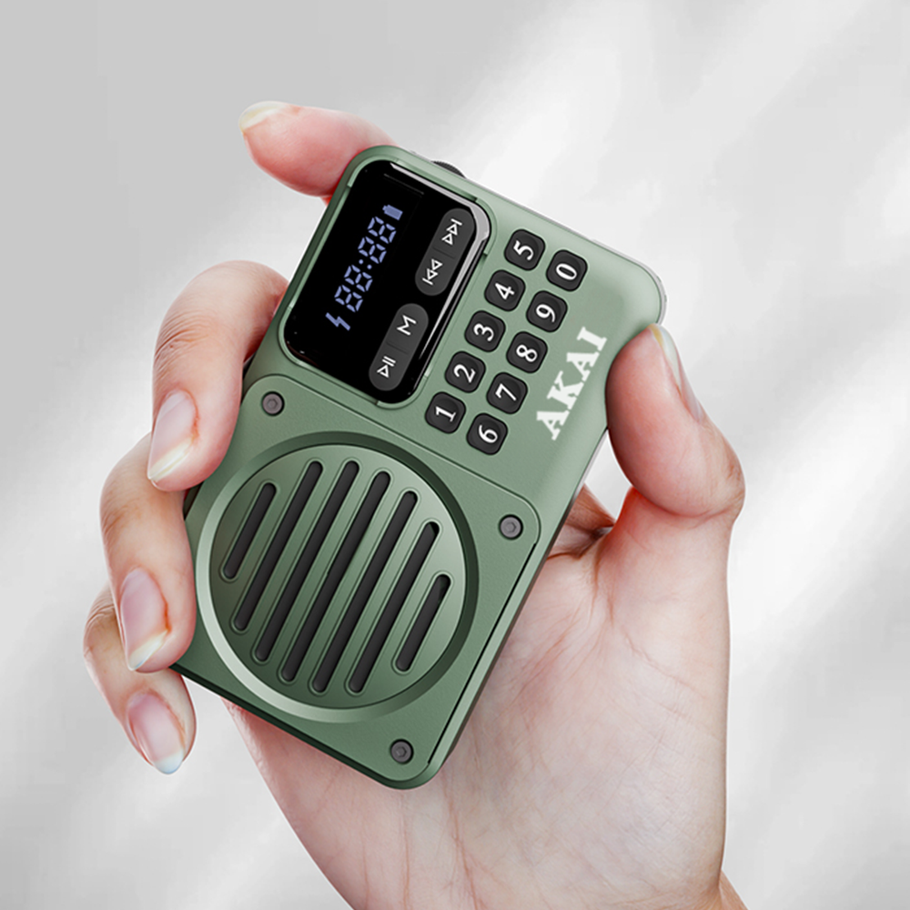 Dłoń trzyma zielone radio AKAI z wyświetlaczem pokazującym cyfry. Radio ma przyciski i głośnik.