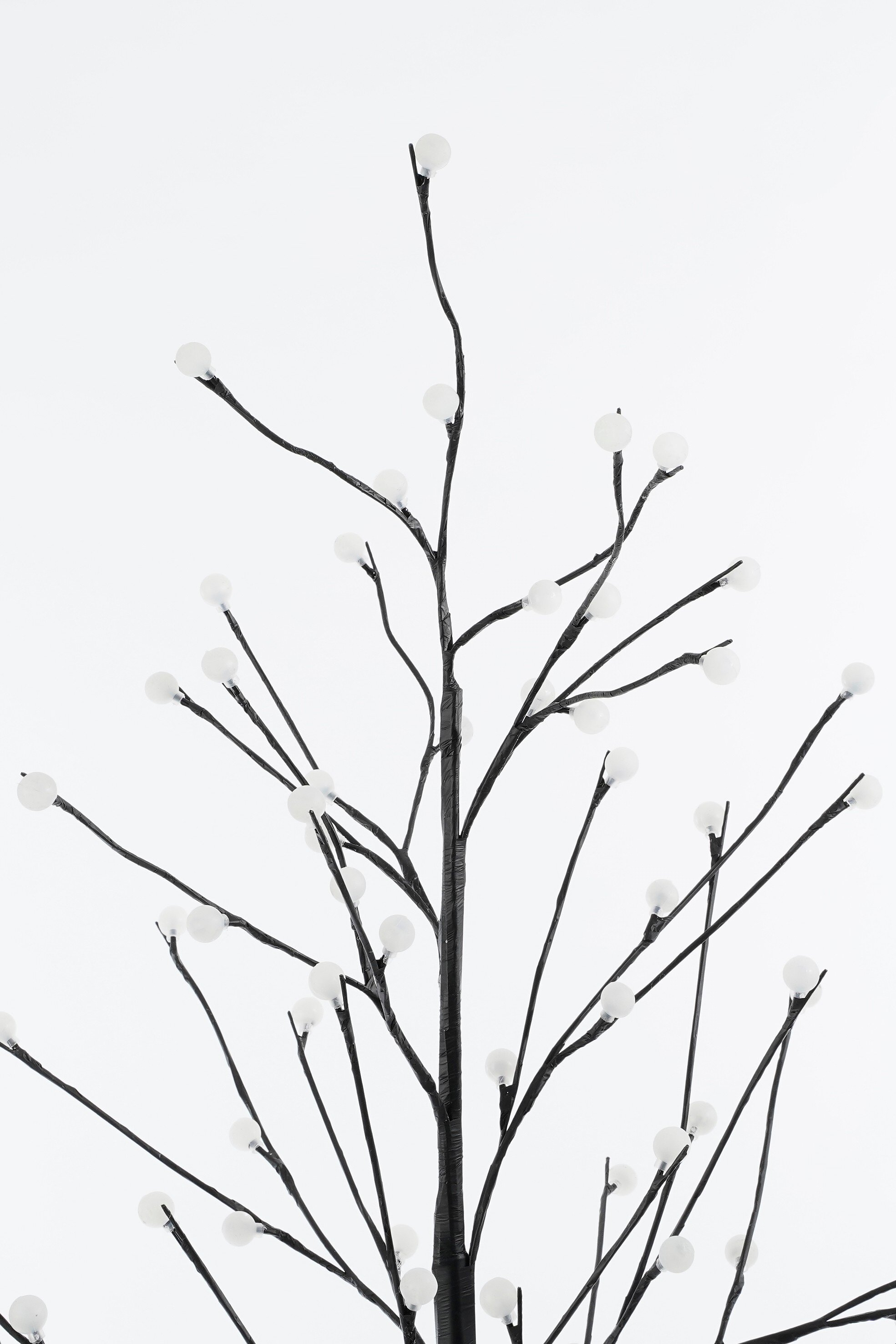 Un arbre décoratif avec des branches noires et de petites lumières blanches sur fond blanc.