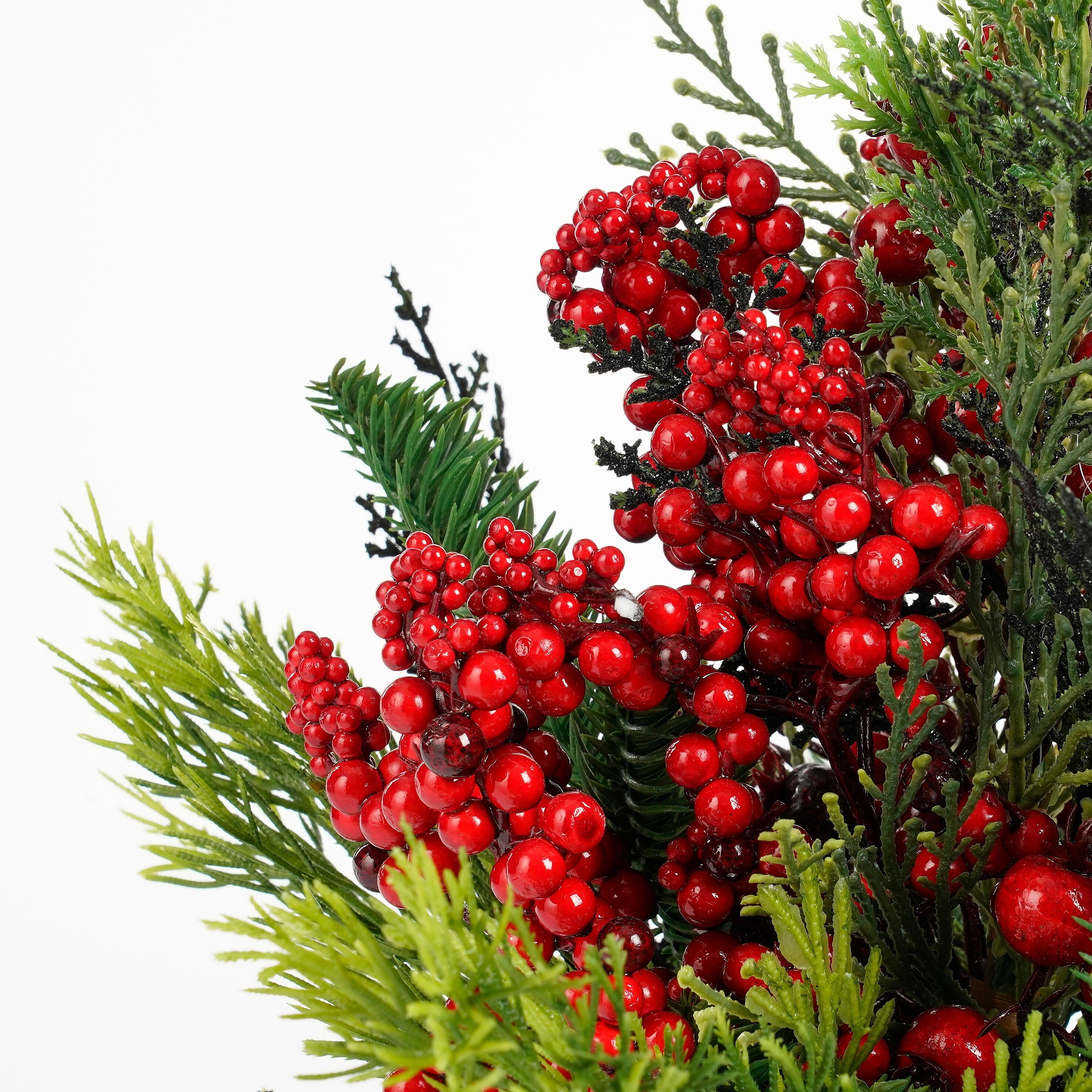 Close-up van een kerstversiering. Rode bessen en groene bladeren op een witte achtergrond.