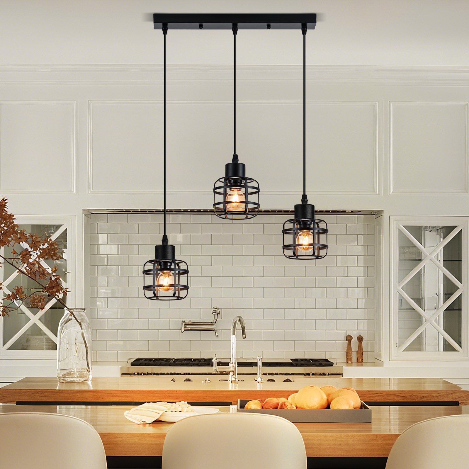 Cocina con tres lámparas colgantes negras, encimera de madera con comida y armarios blancos.