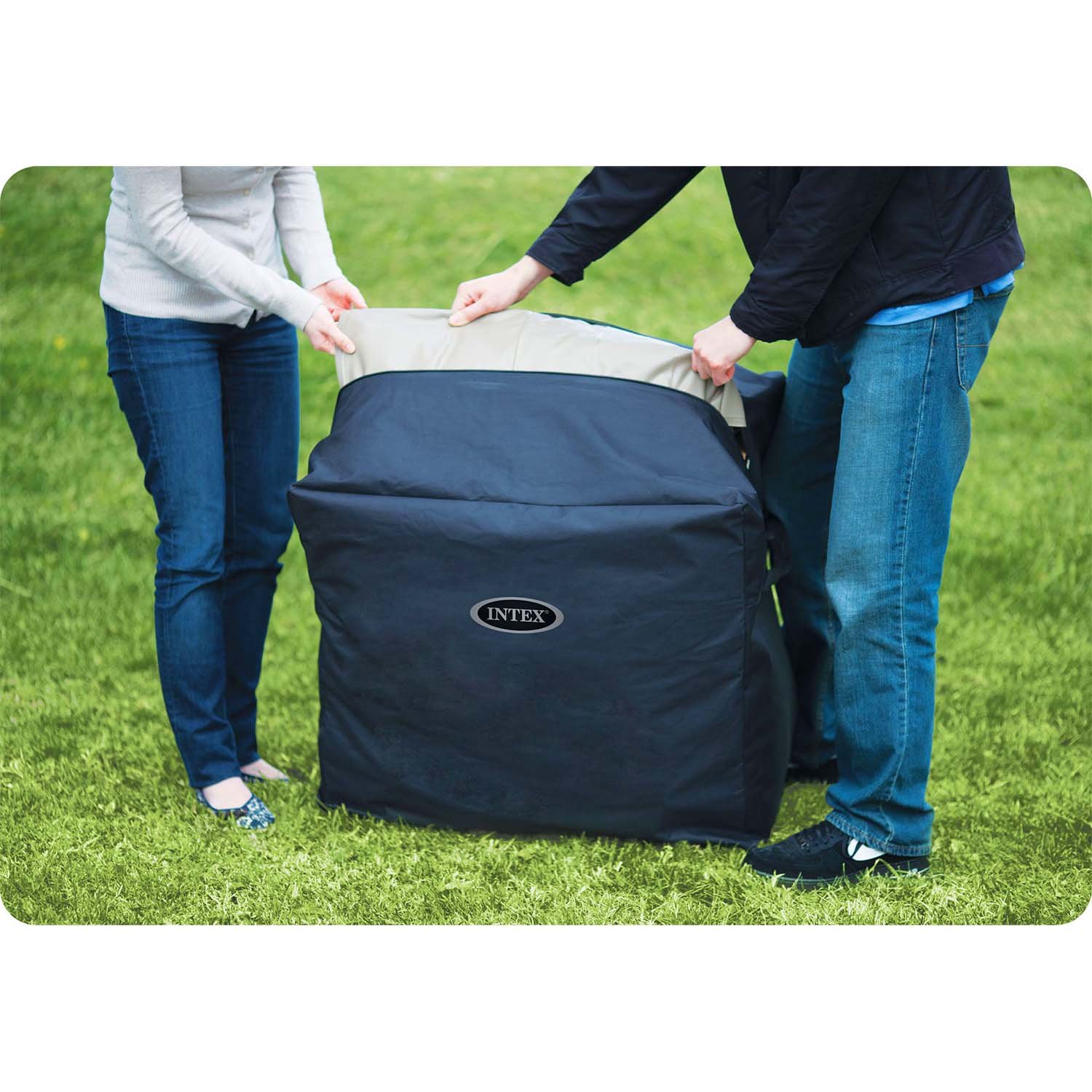 Dwie osoby otwierają czarną torbę Intex na zielonej trawie. Jedna ma na sobie dżinsy i sweter, druga dżinsy i kurtkę.