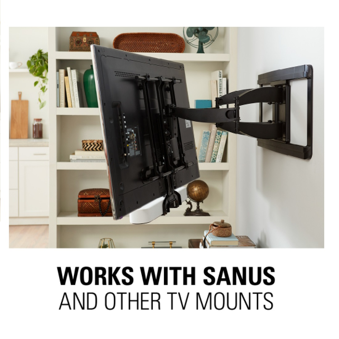 A TV is mounted on a wall bracket. The TV is black, and the bracket is also black. Bookshelves are in the background.