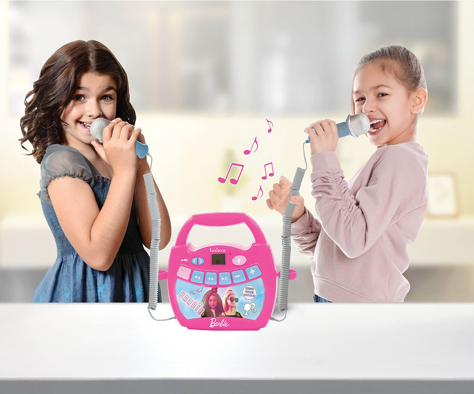 Due ragazze cantano in microfoni, una macchina per karaoke Barbie rosa al centro con note musicali.