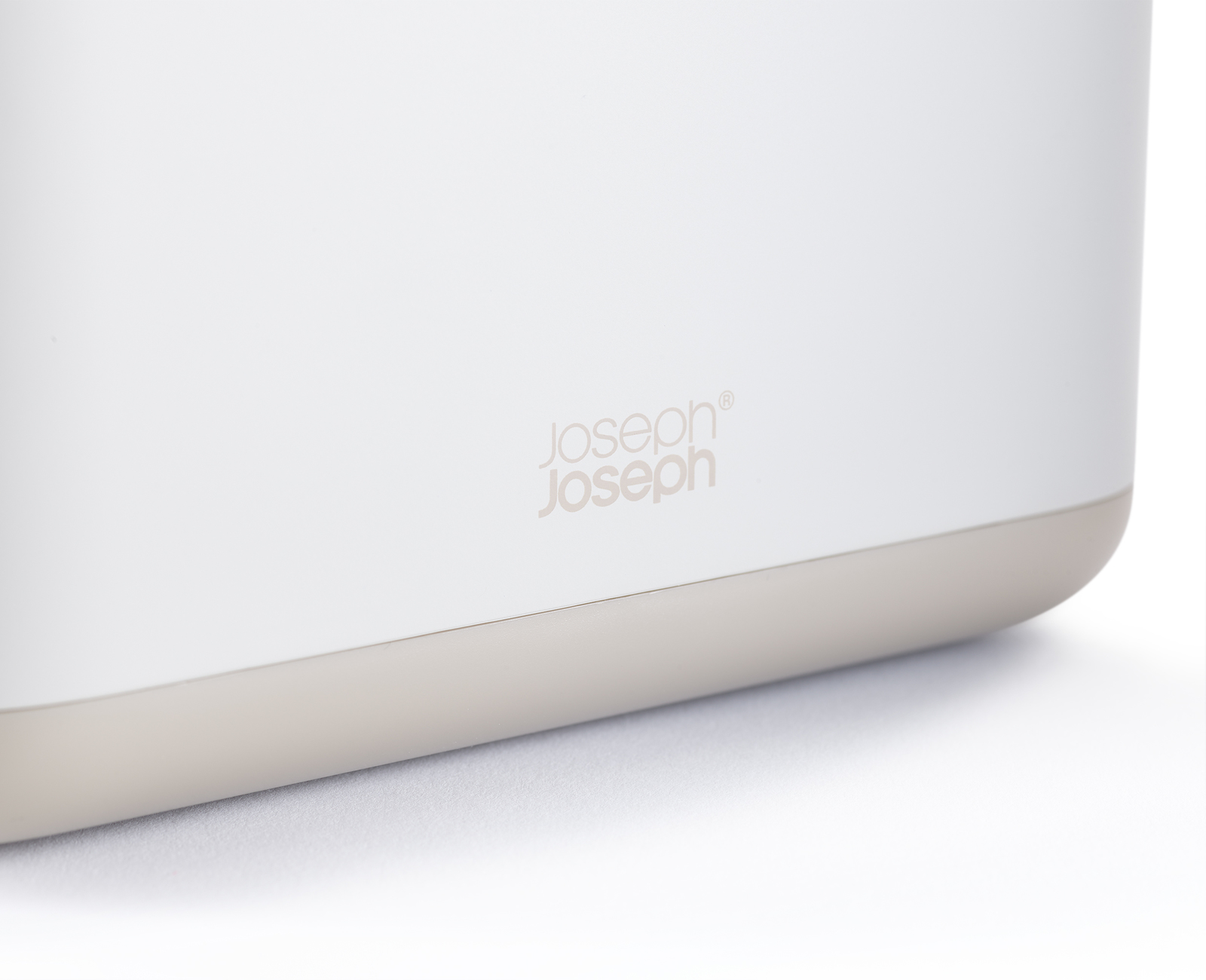 Primer plano de un contenedor blanco con base beige. El logotipo de Joseph Joseph es visible.