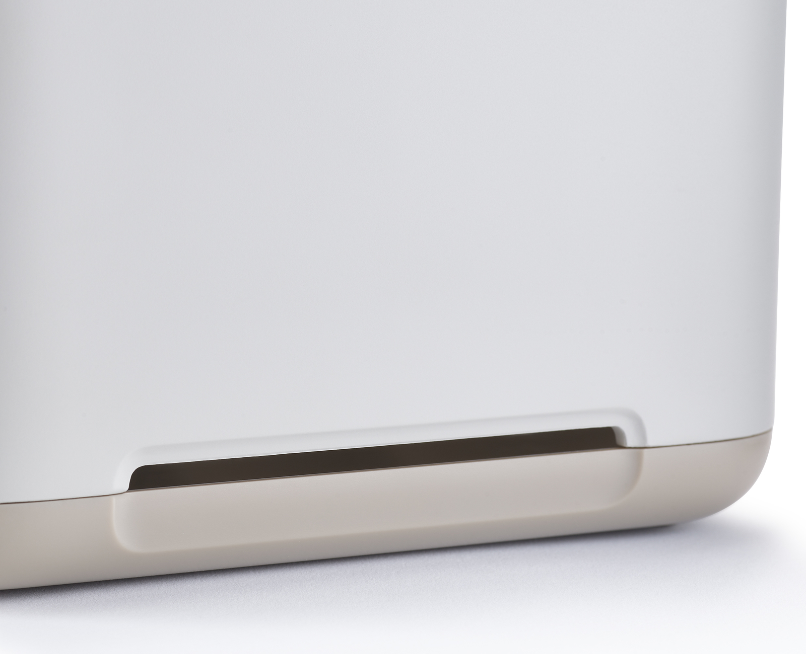 Primer plano de un objeto blanco y beige. Tiene un área empotrada con interior oscuro y bordes redondeados.