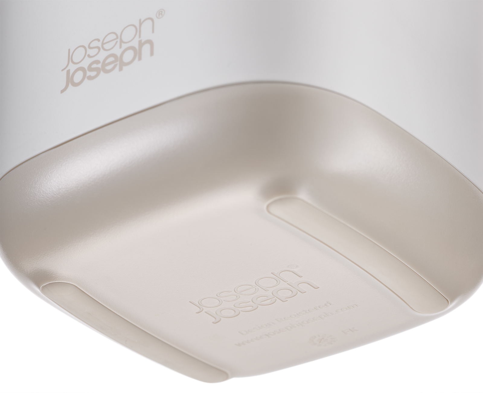 Primer plano de un objeto de plástico blanco y beige con esquinas redondeadas y el logotipo de Joseph Joseph.
