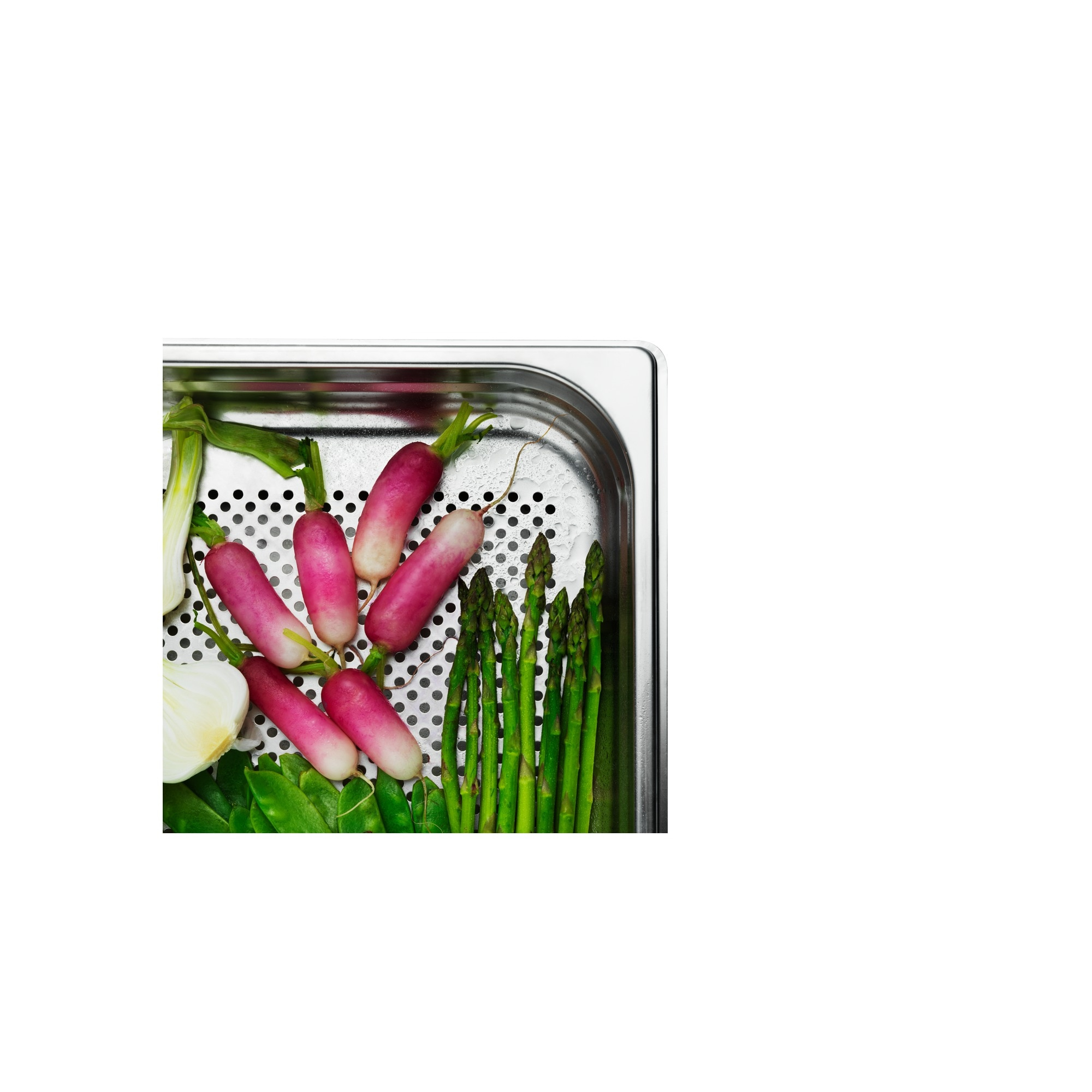 Ein Metalltablett enthält Radieschen, Spargel und anderes Gemüse. Die Radieschen sind rosa und weiß. Spargel ist grün.