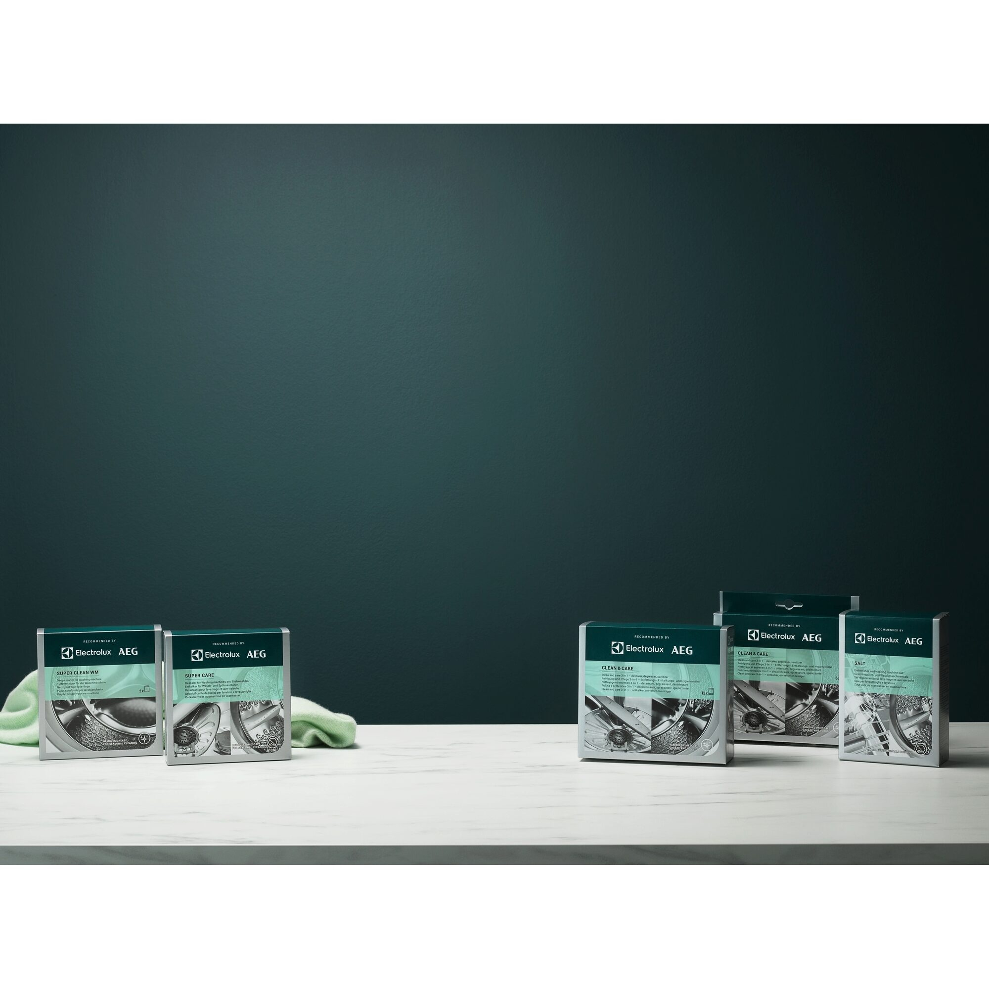 Scatole di prodotti con marchio Electrolux AEG su superficie bianca con sfondo verde scuro.