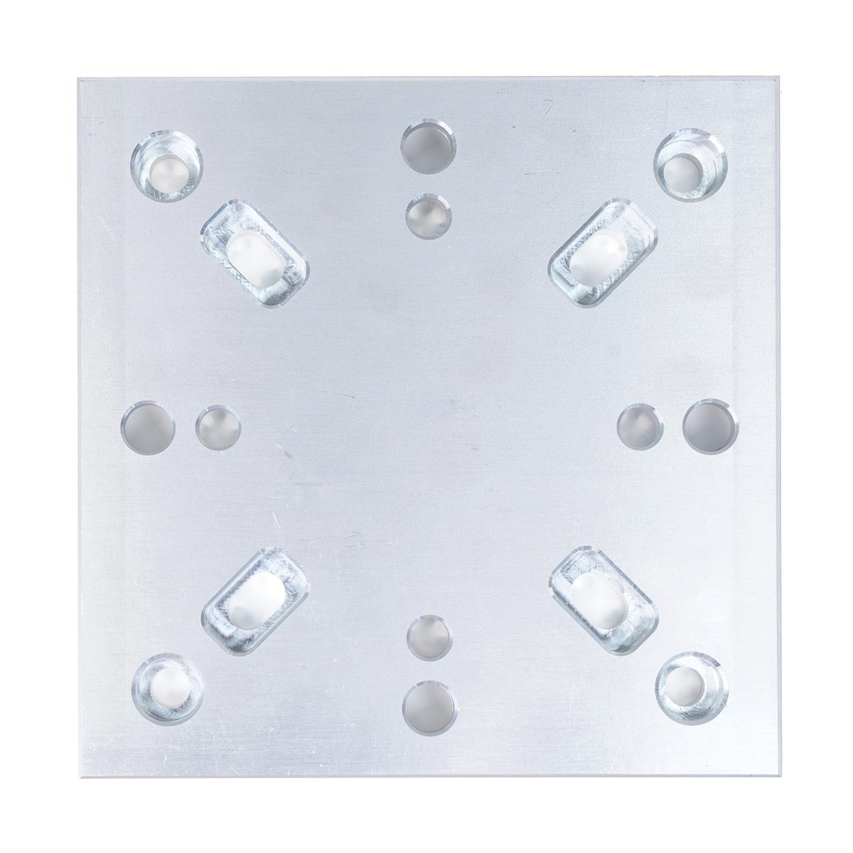 A square metal plate with circular and rectangular holes. The plate is silver with several holes of different sizes.