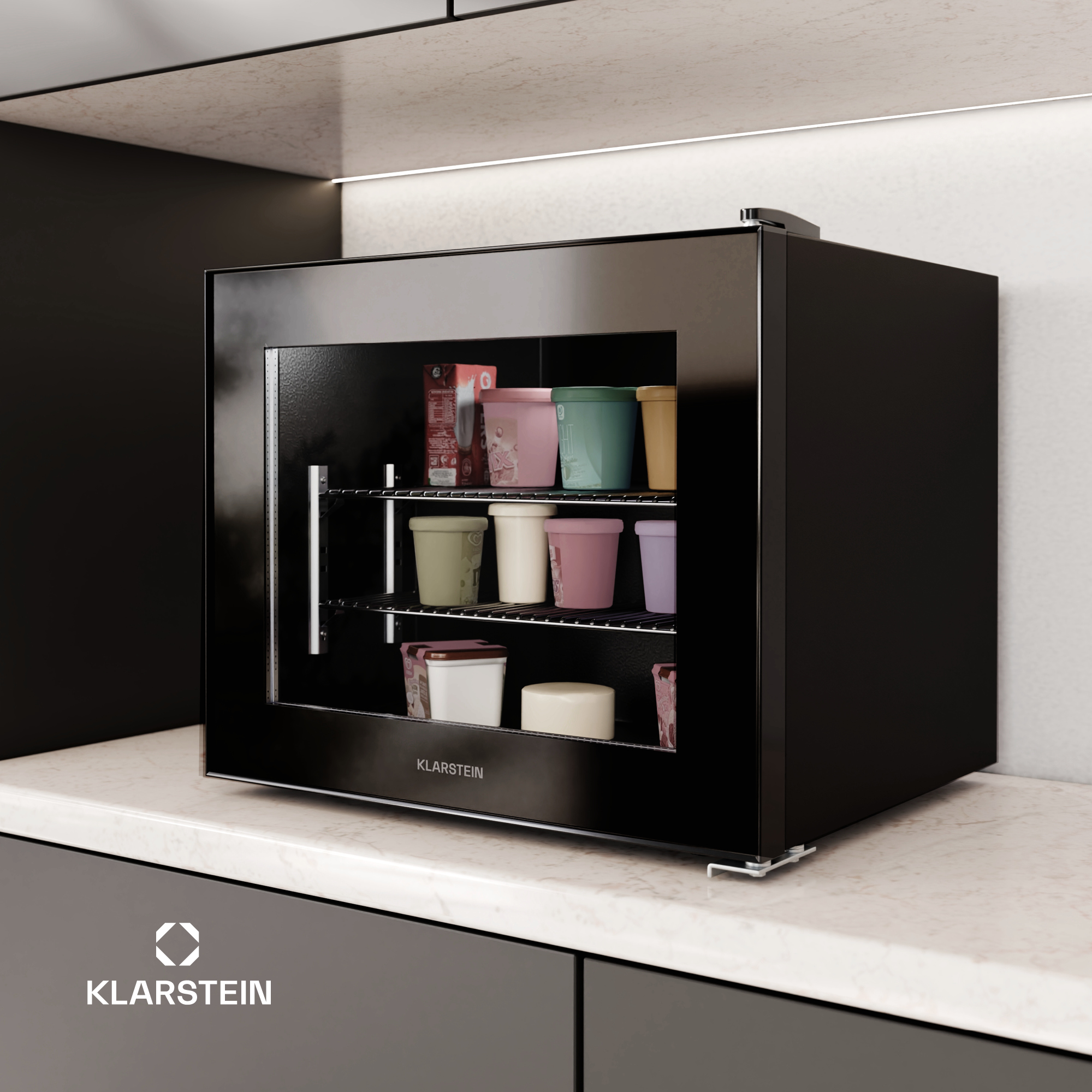 Un mini-frigorifero nero su un piano di lavoro. Contiene contenitori di gelato di vari colori. Il marchio è Klarstein.