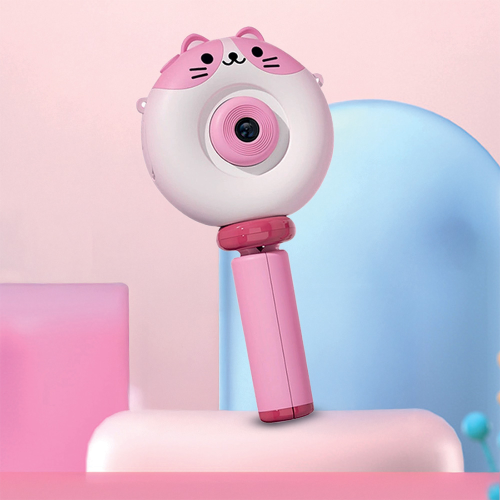 Pembe ve beyaz, kedi yüzü şeklinde oyuncak kamera. Pembe bir sapı var. Arka plan pembe ve mavi şekiller içerir.