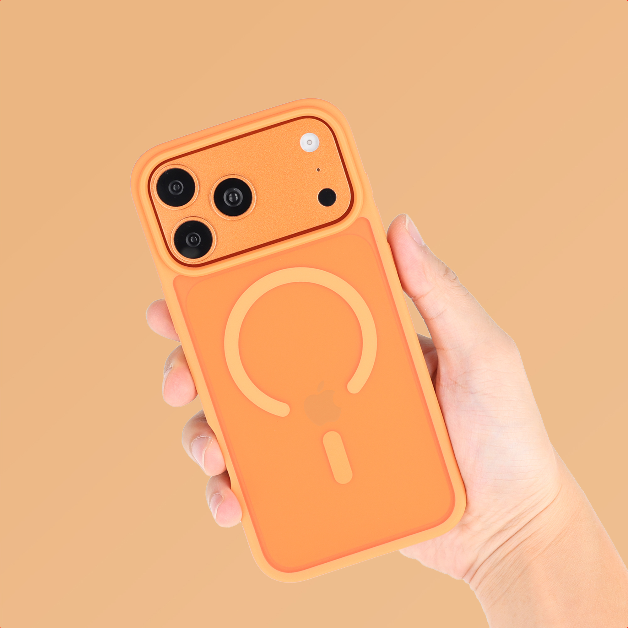 Een hand die een oranje telefoonhoes vasthoudt met een Apple-logo. De hoes heeft drie camera-uitsparingen en een cirkelvormig ontwerp.
