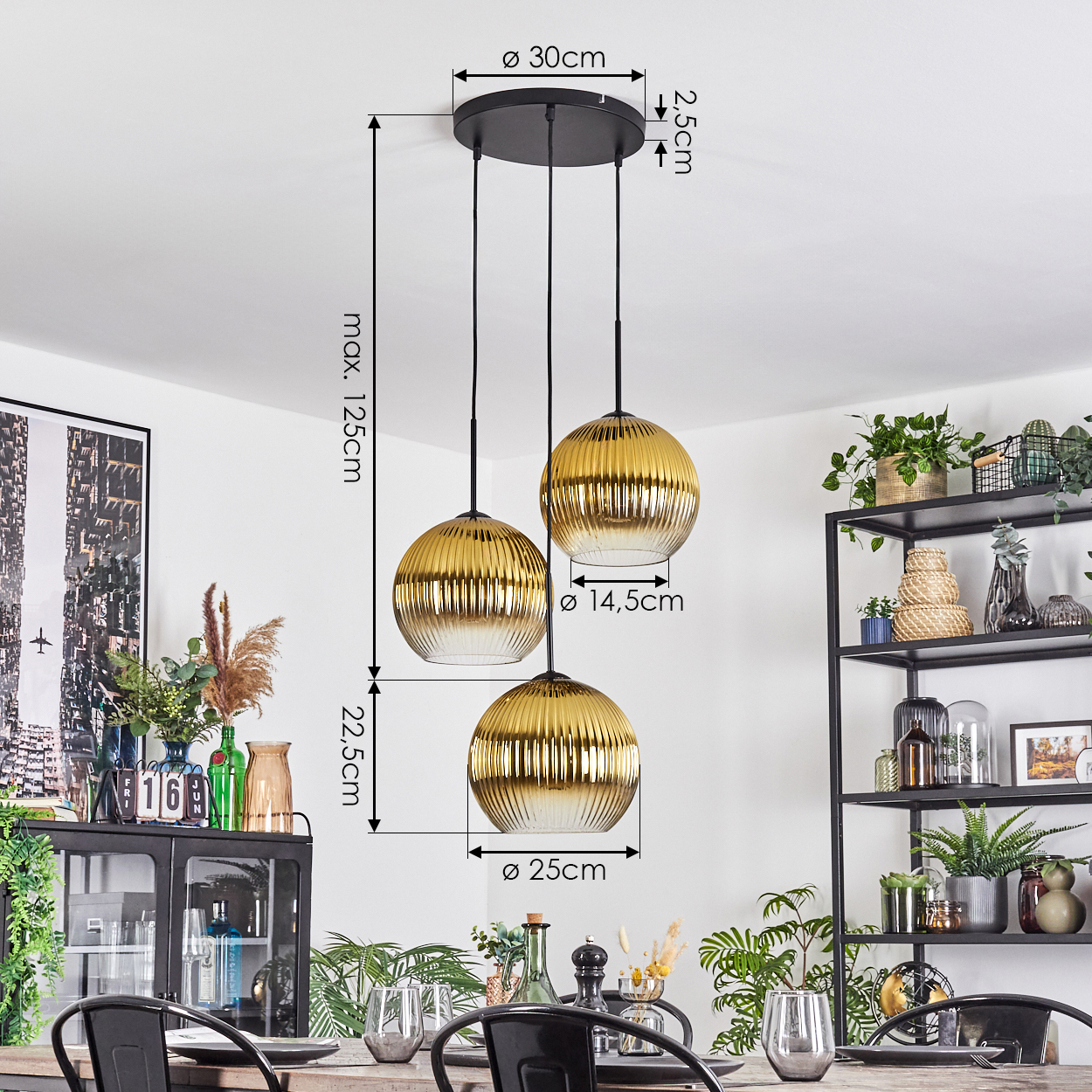 Drei goldene Pendelleuchten hängen von der Decke. Darunter ein gedeckter Esstisch mit Pflanzen und Deko im Hintergrund.