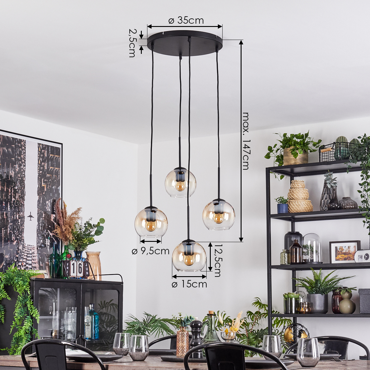 Vierflammige Pendelleuchte mit Glasschirmen über einem Esstisch. Pflanzen und ein schwarzes Metallregal sind im Hintergrund zu sehen.