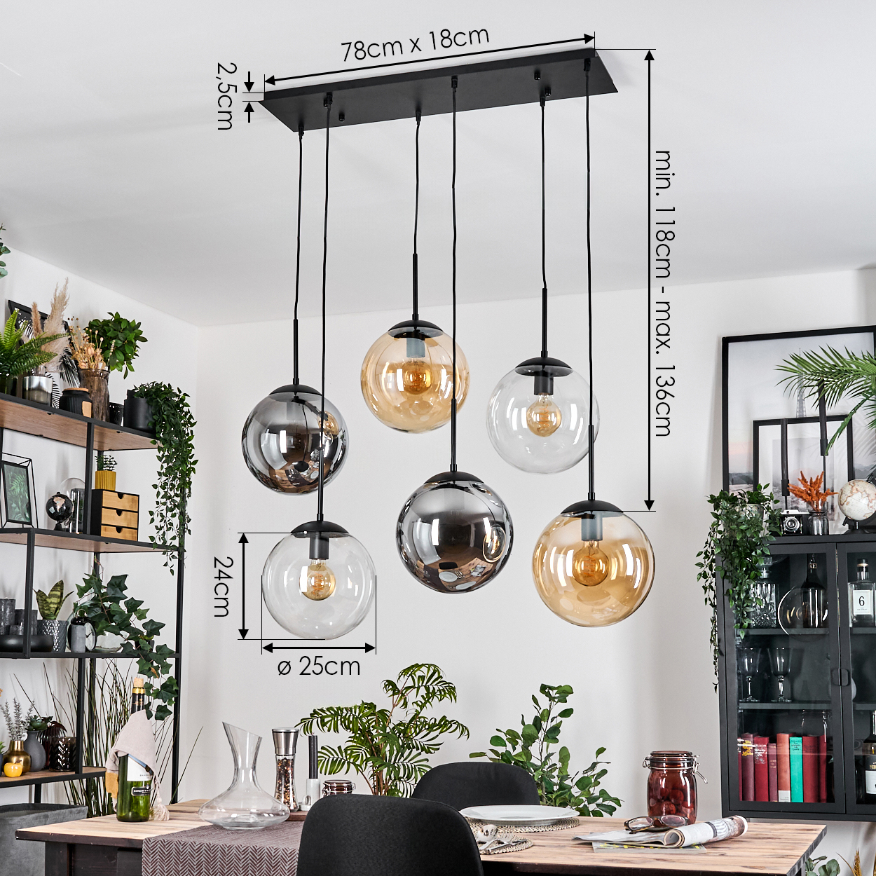 Ein modernes Esszimmer mit einem schwarzen Kronleuchter mit sechs Glaskugeln. Maße sind angegeben. Pflanzen und ein Esstisch sind zu sehen.
