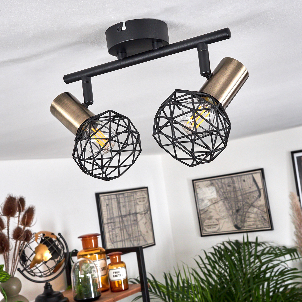 Deckenleuchte mit zwei Lampen. Jede Lampe hat einen schwarzen geometrischen Schirm und einen goldfarbenen zylindrischen Sockel. Die Decke ist weiß.