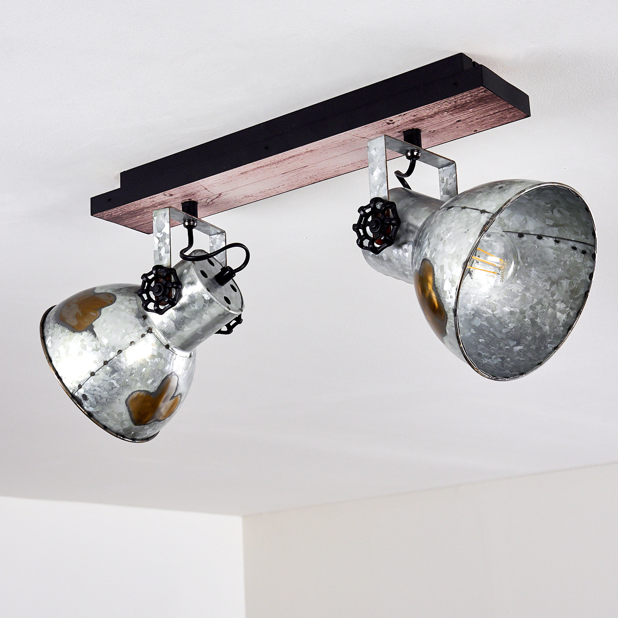 Deckenleuchte mit zwei Metallstrahlern, montiert auf einem Holzbalken, mit schwarzen Details und weißem Deckenhintergrund.
