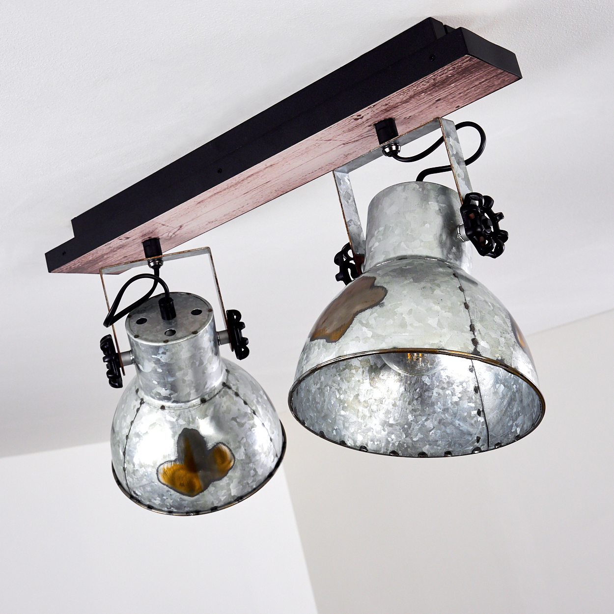 Deckenleuchte mit zwei Metall-Strahlern, montiert auf einem Holzbalken, vor weißer Decke.