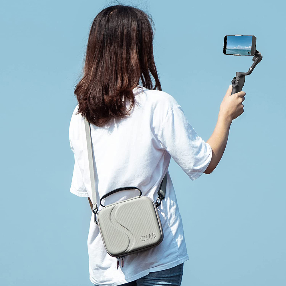 Eine Frau hält ein Telefon auf einem Gimbal und ist vom Betrachter abgewandt. Sie trägt ein weißes Hemd und hat eine graue Tasche.