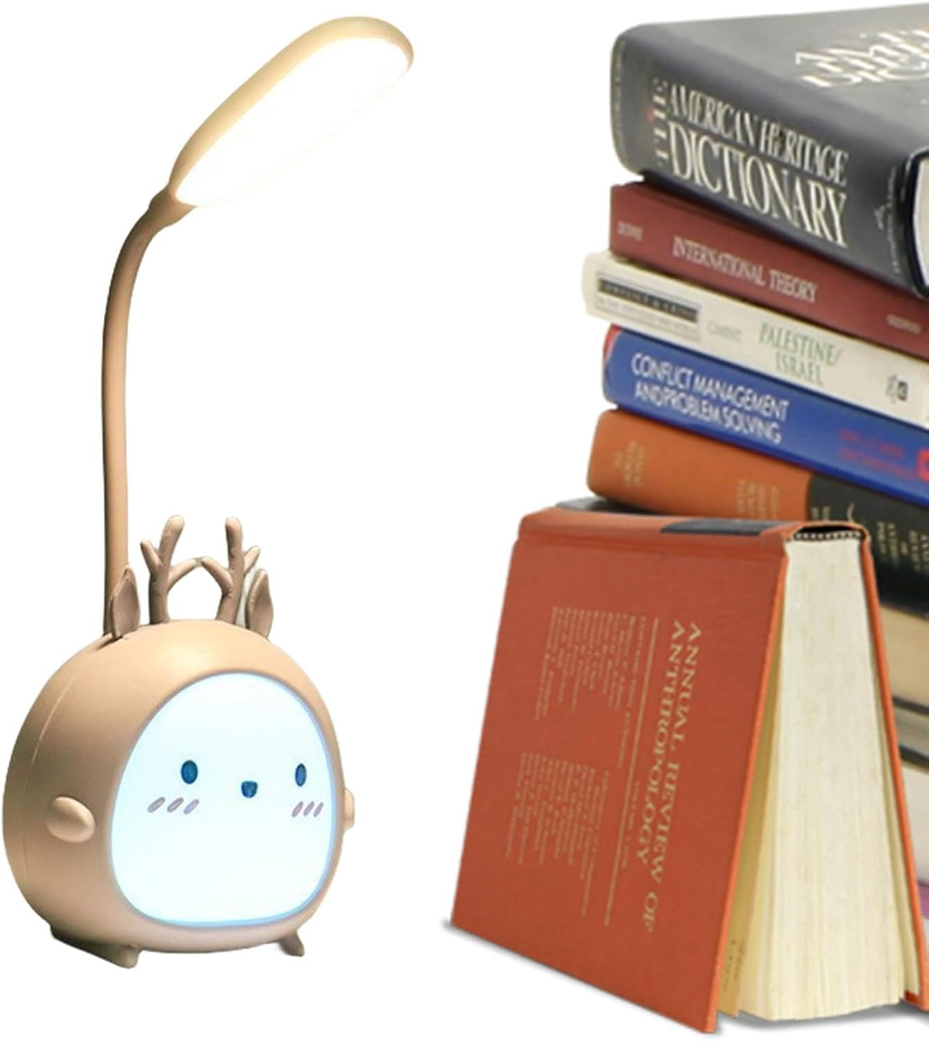 Eine Schreibtischlampe in Form eines Hirsches steht neben einem Stapel Bücher, darunter ein Wörterbuch und Bücher über Theorie.