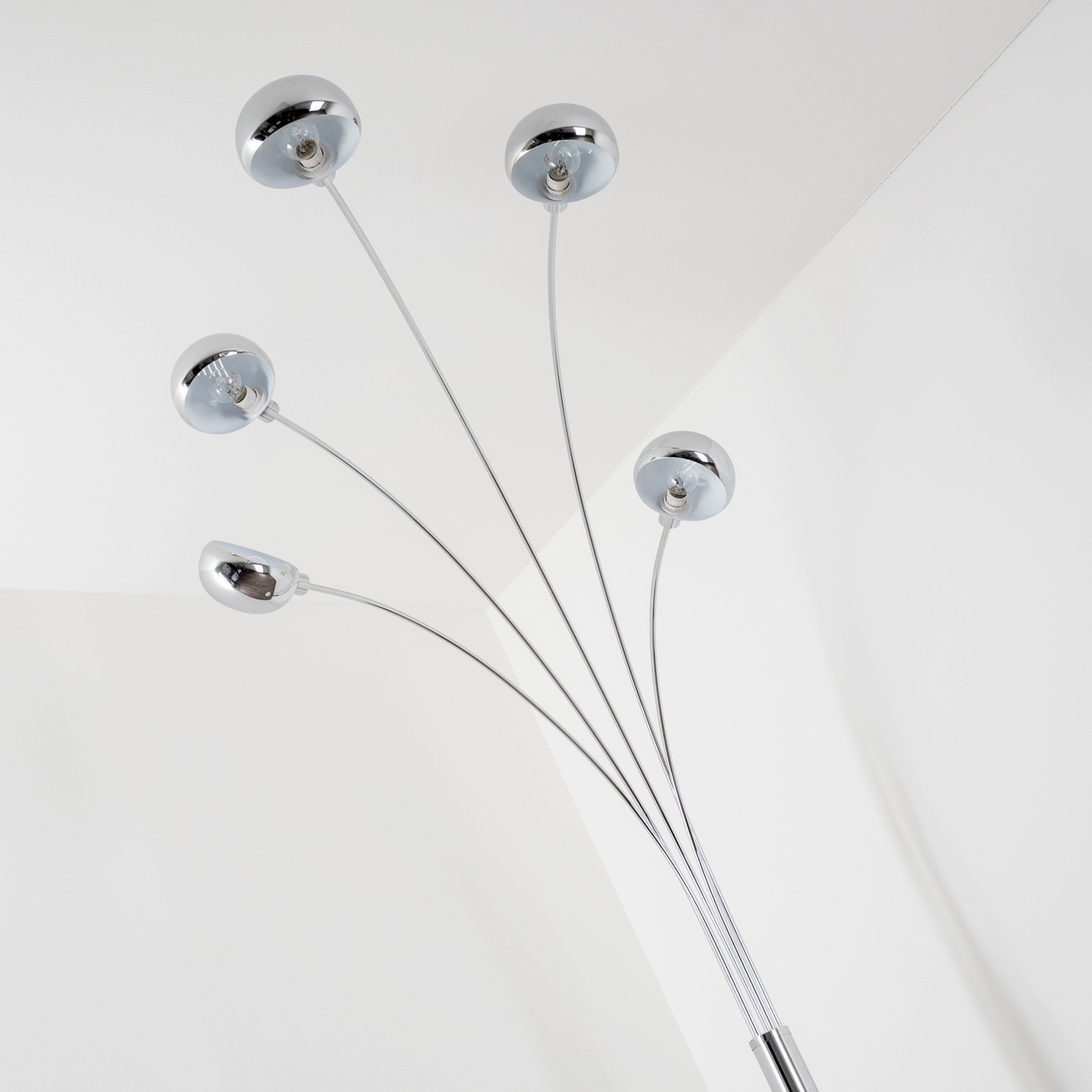 Eine verchromte Stehlampe mit fünf Lichtern. Jedes Licht hat eine silberne Glühbirne und ist in verschiedenen Winkeln vor weißem Hintergrund positioniert.