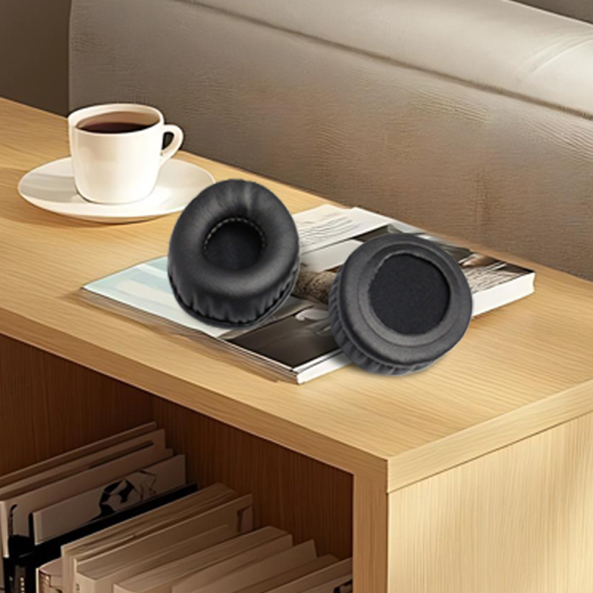 Dwie czarne poduszki do słuchawek na magazynie, filiżanka kawy i stos książek na drewnianym stole.