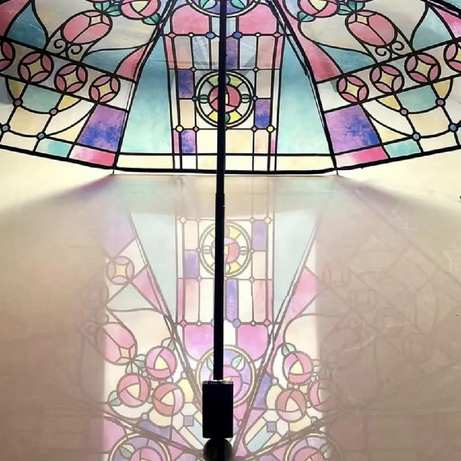Ein bunter Buntglas-Regenschirm spiegelt sein Muster wider. Schwarzer Stiel in der Mitte, der einen Schatten wirft. Rosen und kreisförmige Designs.