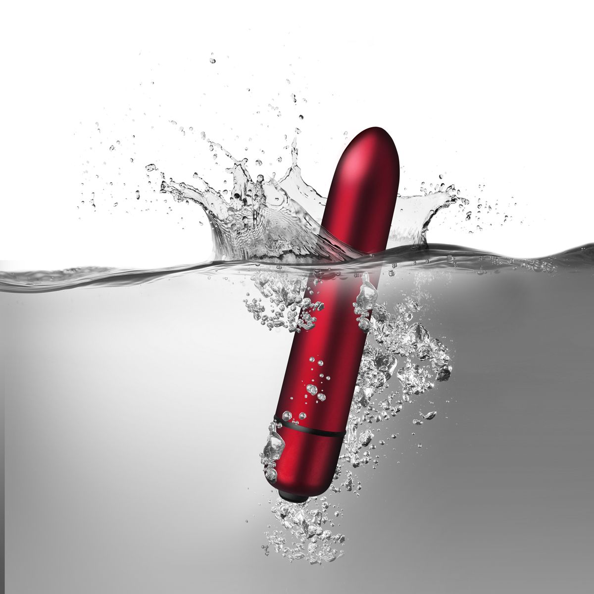 Ein roter Vibrator ist in Wasser getaucht und erzeugt Spritzer und Blasen. Der Hintergrund ist ein Grau-Weiß-Verlauf.