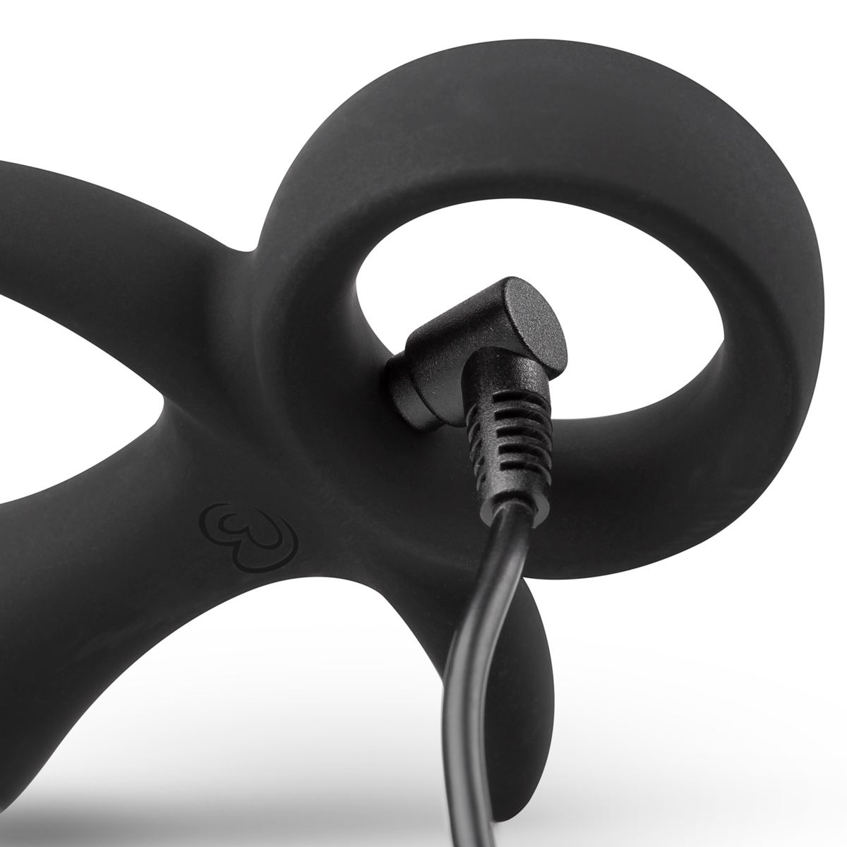 Schwarzes Sexspielzeug mit kreisförmigem Design. Ein schwarzes Kabel ist eingesteckt. Der Hintergrund ist weiß.