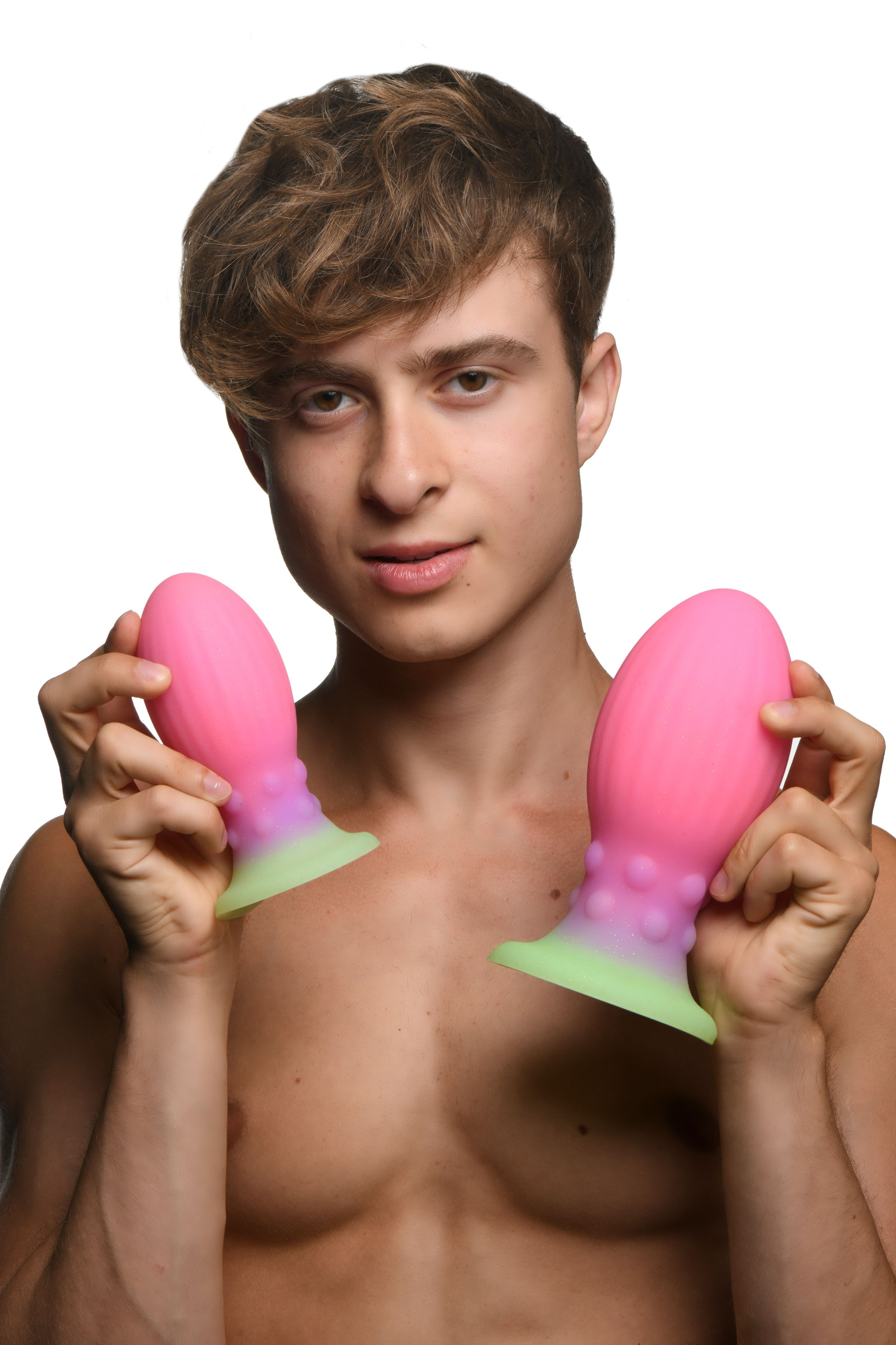 Ein Mann hält zwei rosa Sexspielzeuge mit grünen Basen vor weißem Hintergrund.