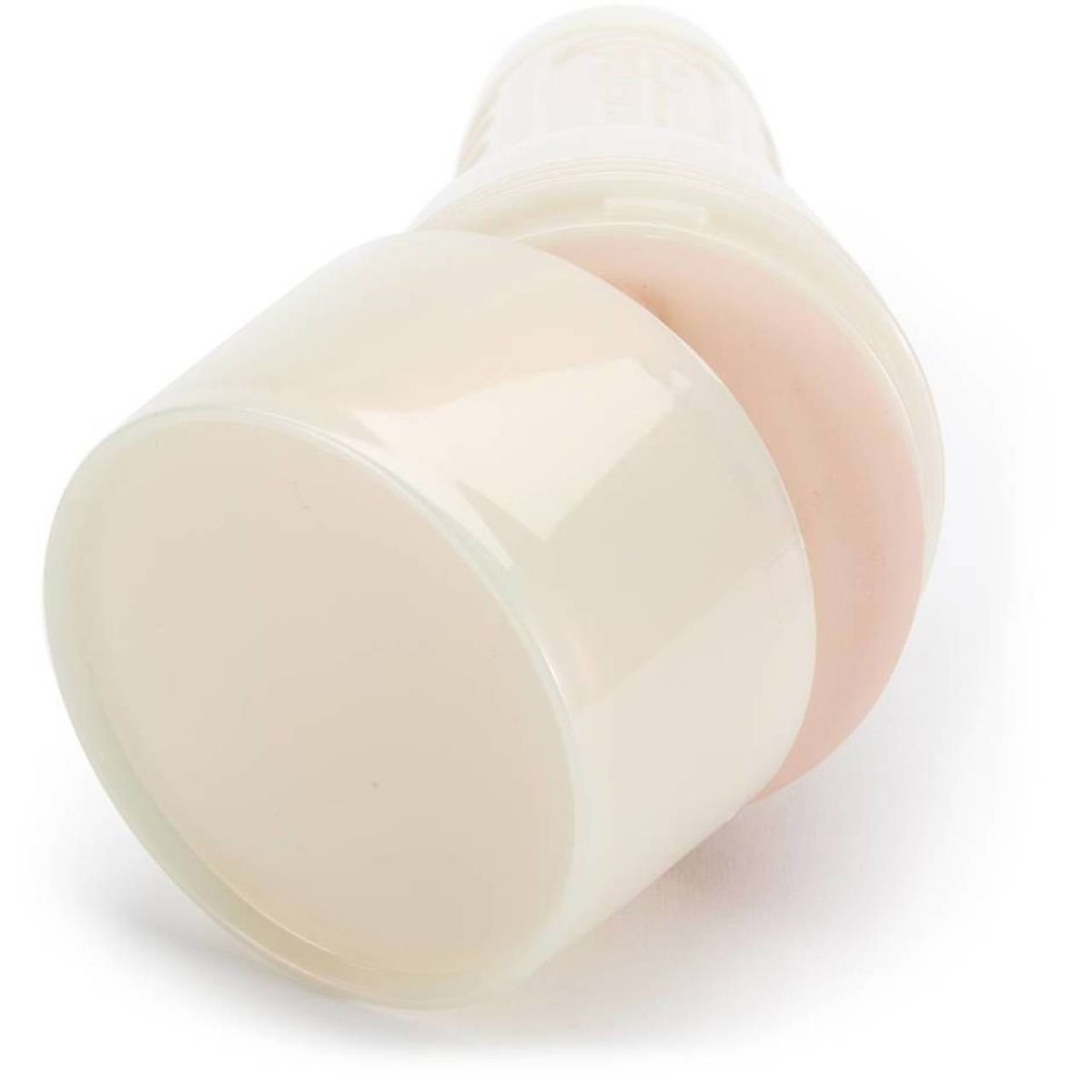 Eine cremefarbene Babyflasche mit einem rosafarbenen Abschnitt. Die Flasche liegt auf einer weißen Oberfläche und zeigt ihr Seitenprofil.