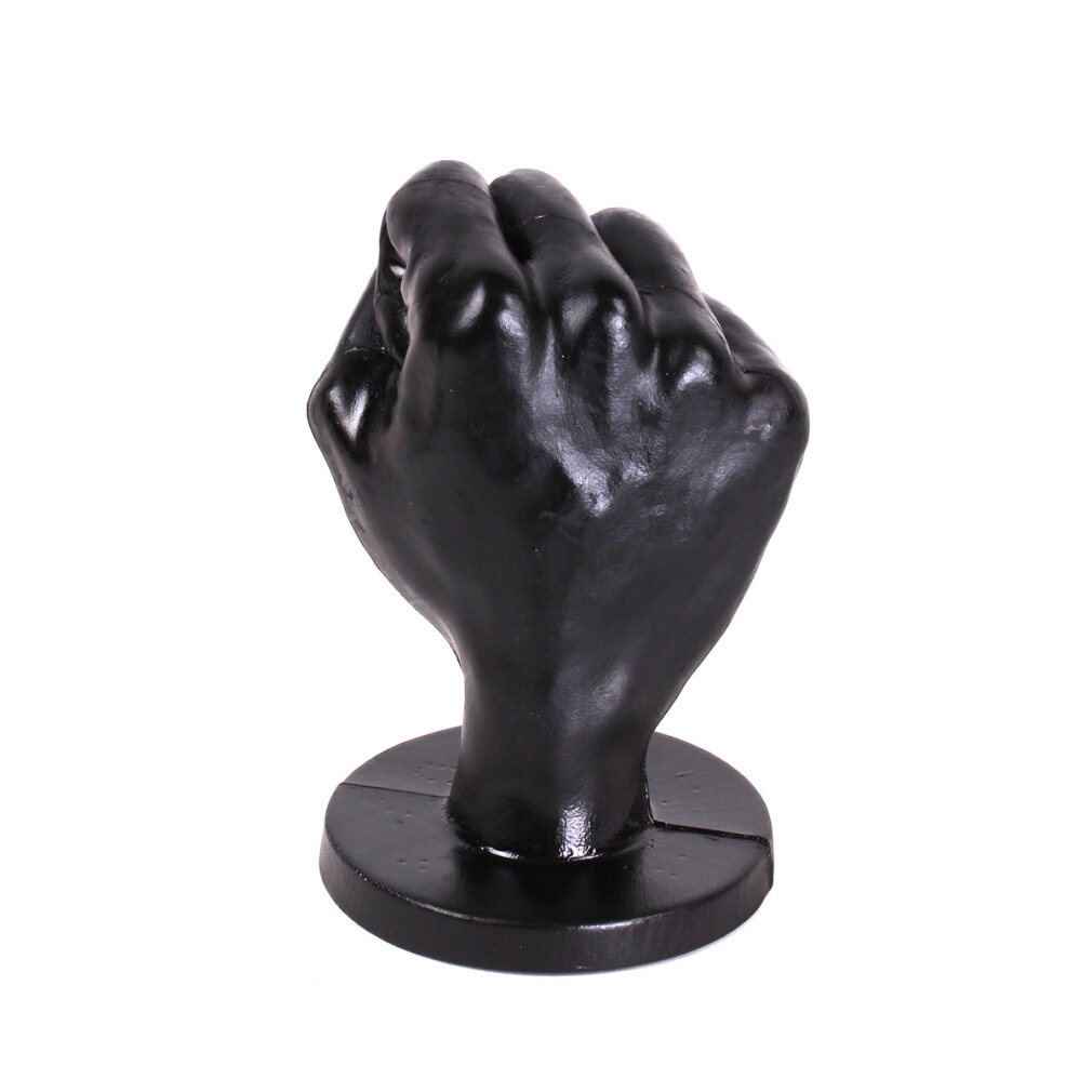 Eine schwarze Faustskulptur auf einem runden Sockel. Die Faust ist geschlossen, Knöchel sind sichtbar. Der Hintergrund ist weiß.