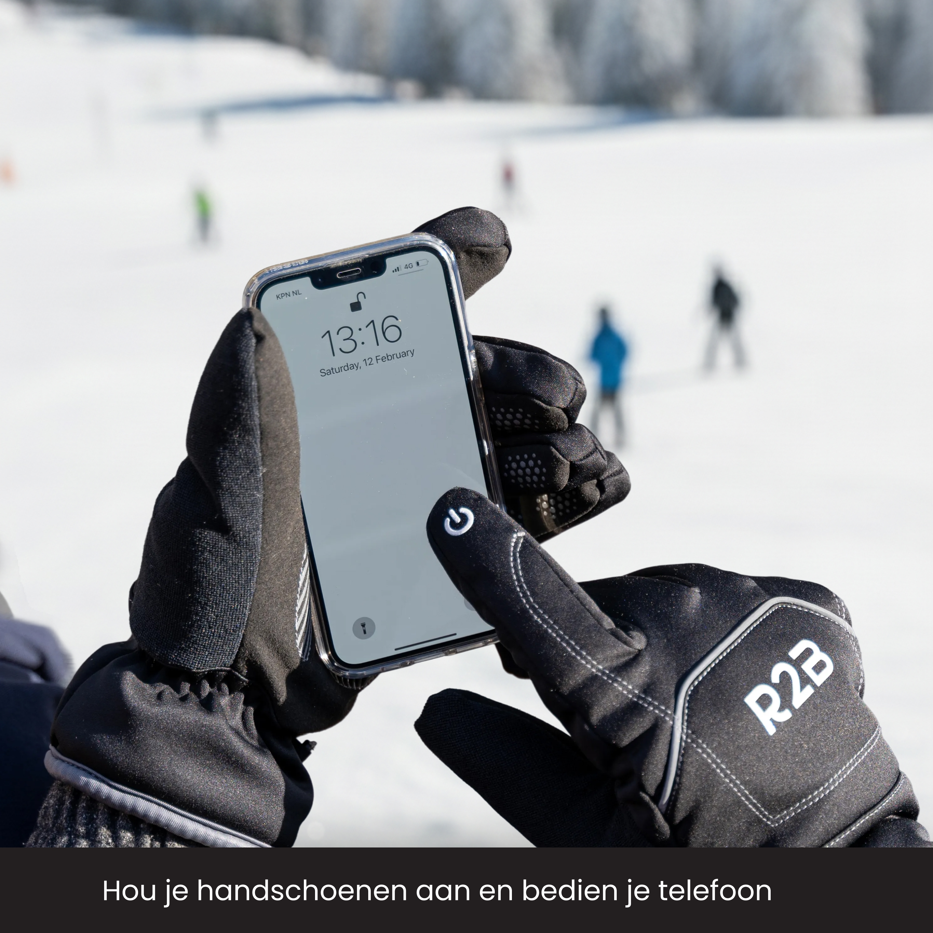 Hands in black gloves holding a phone displaying time and date, in a snowy landscape.