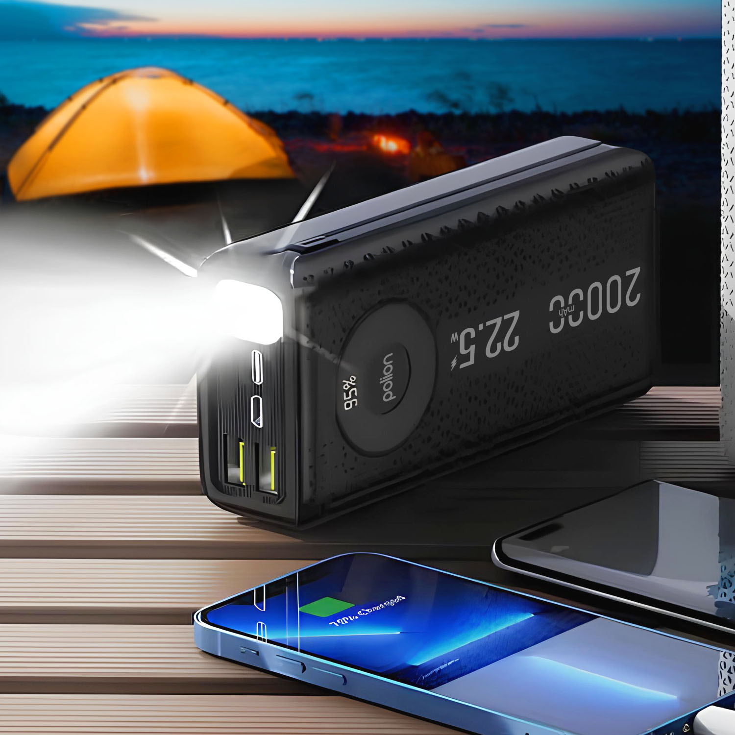 Czarny power bank ze światłem ładuje telefon. Namiot znajduje się w tle w pobliżu zbiornika wodnego.