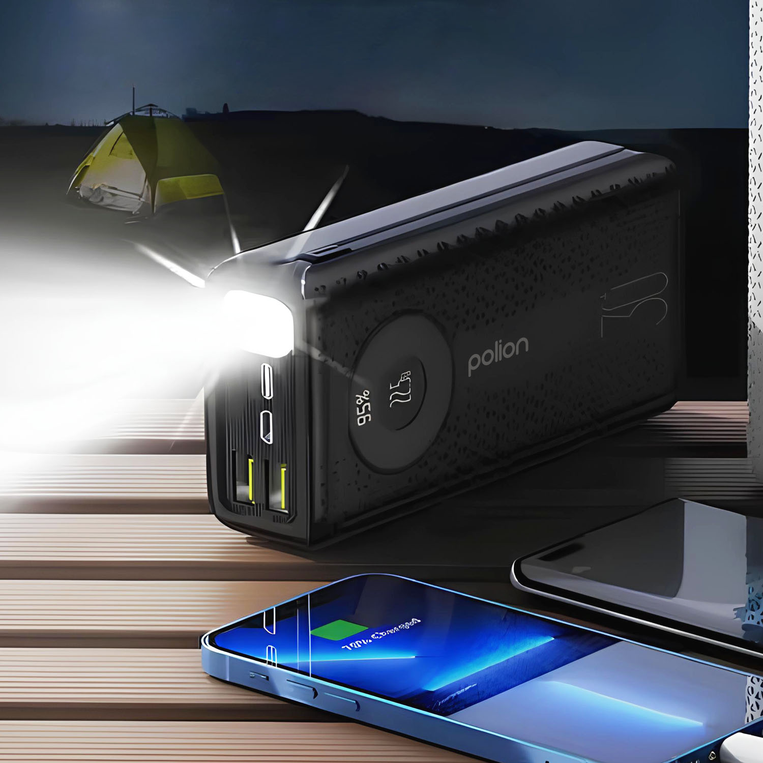 Czarny power bank ze światłem ładuje telefon. Namiot jest w tle. Scena jest ciemna.