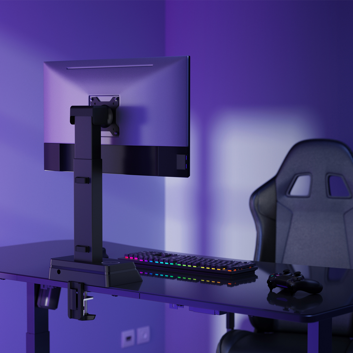 Un'impostazione di gioco con monitor, tastiera e controller su una scrivania nera. Una sedia da gioco è sullo sfondo. La stanza è viola.