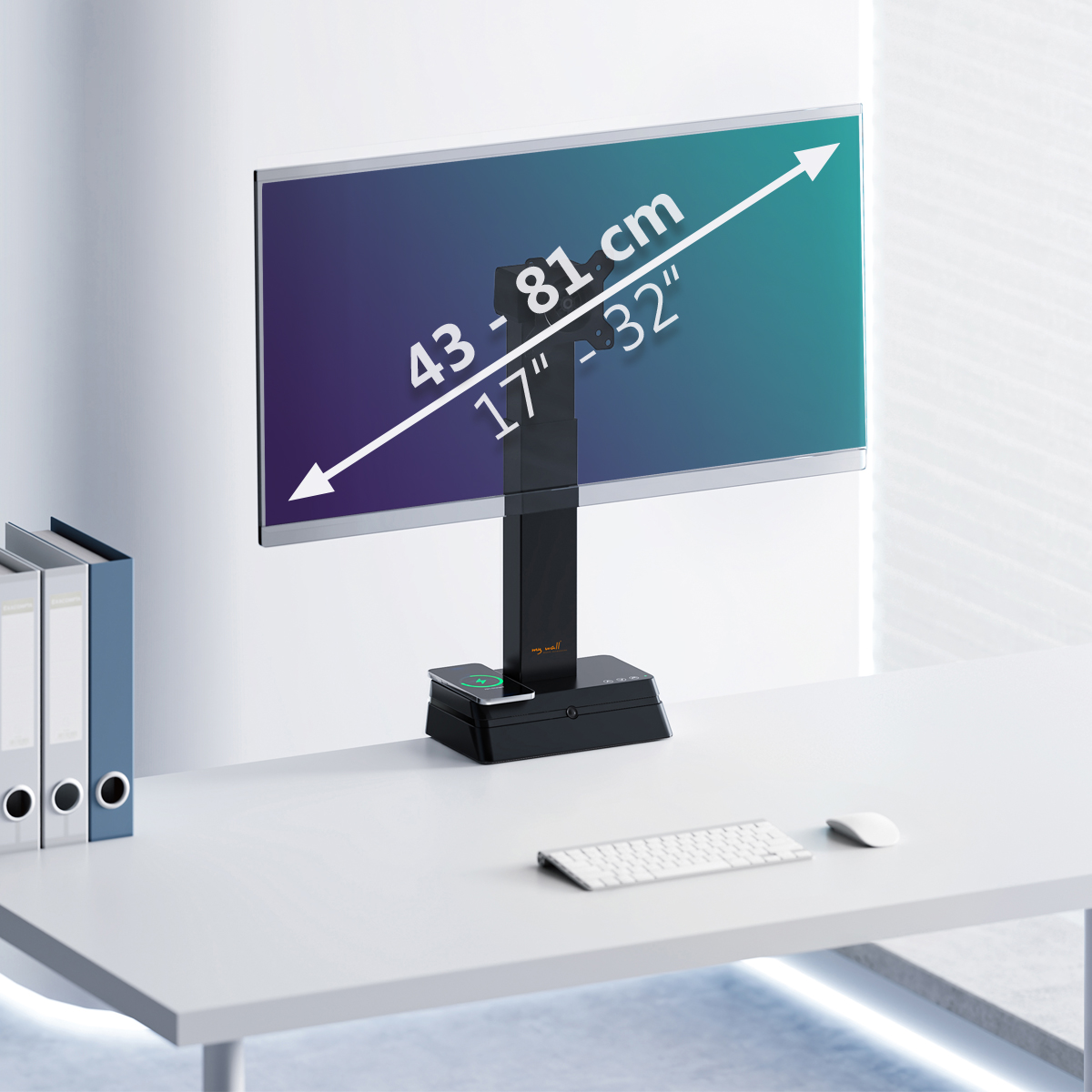 Un monitor su un supporto nero è su una scrivania bianca, con tastiera, mouse e raccoglitori. Lo schermo mostra le dimensioni.