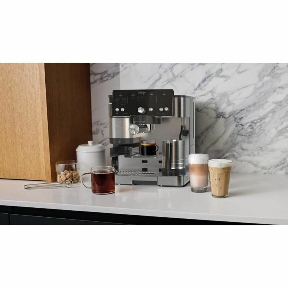 Eine Ninja-Espressomaschine mit verschiedenen Kaffeegetränken. Ein klares Glas Kaffee steht davor. Marmorhintergrund.