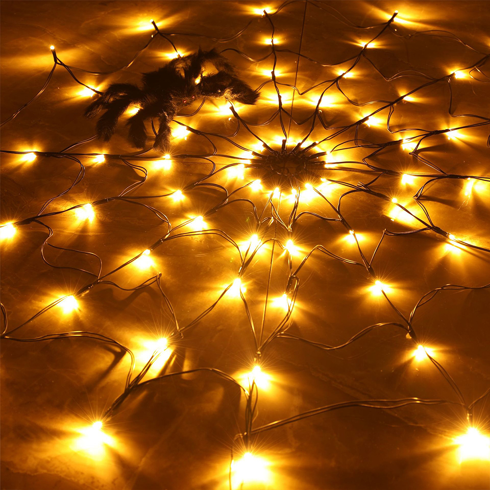 Ein Spinnennetz aus Lichtern mit einer schwarzen Spinne. Die Lichter sind gelb und der Hintergrund ist dunkel.