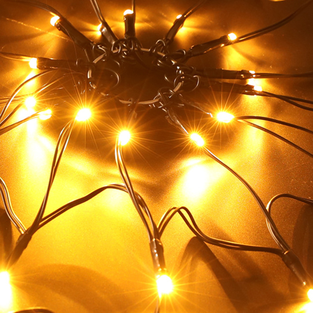 Nahaufnahme von Lichterketten. Helle gelbe Lichter auf schwarzen Drähten vor gelbem Hintergrund. Einige Lichter sind fokussiert, andere unscharf.