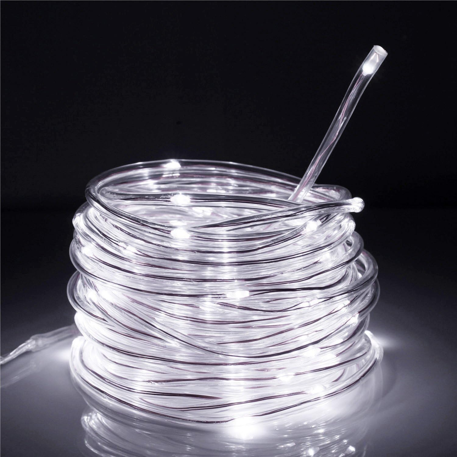 Eine aufgerollte Schnur mit weißen LED-Leuchten. Ein gerader Abschnitt der Schnur erstreckt sich nach oben. Der Hintergrund ist dunkel mit einer reflektierenden Oberfläche.