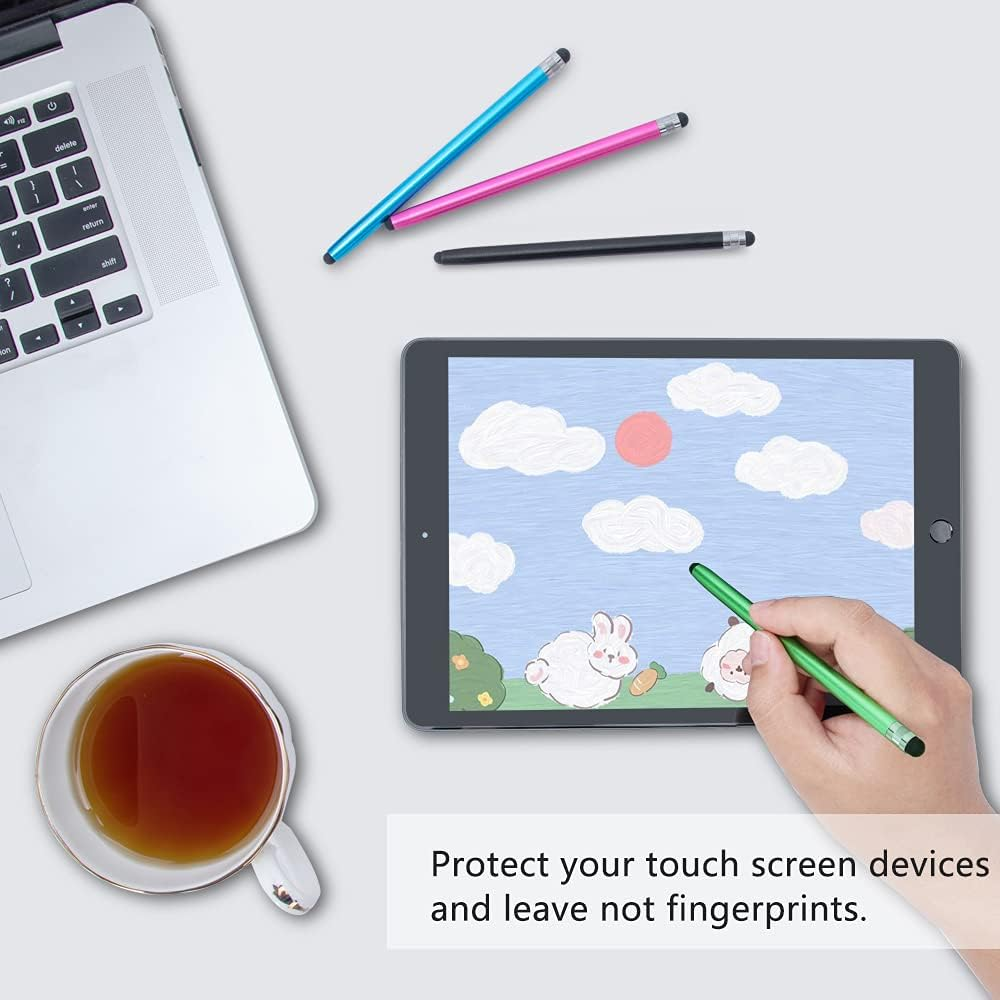 Stifte und ein Tablet mit einer Cartoon-Szene, ein Laptop und eine Tasse Tee auf einer weißen Oberfläche.