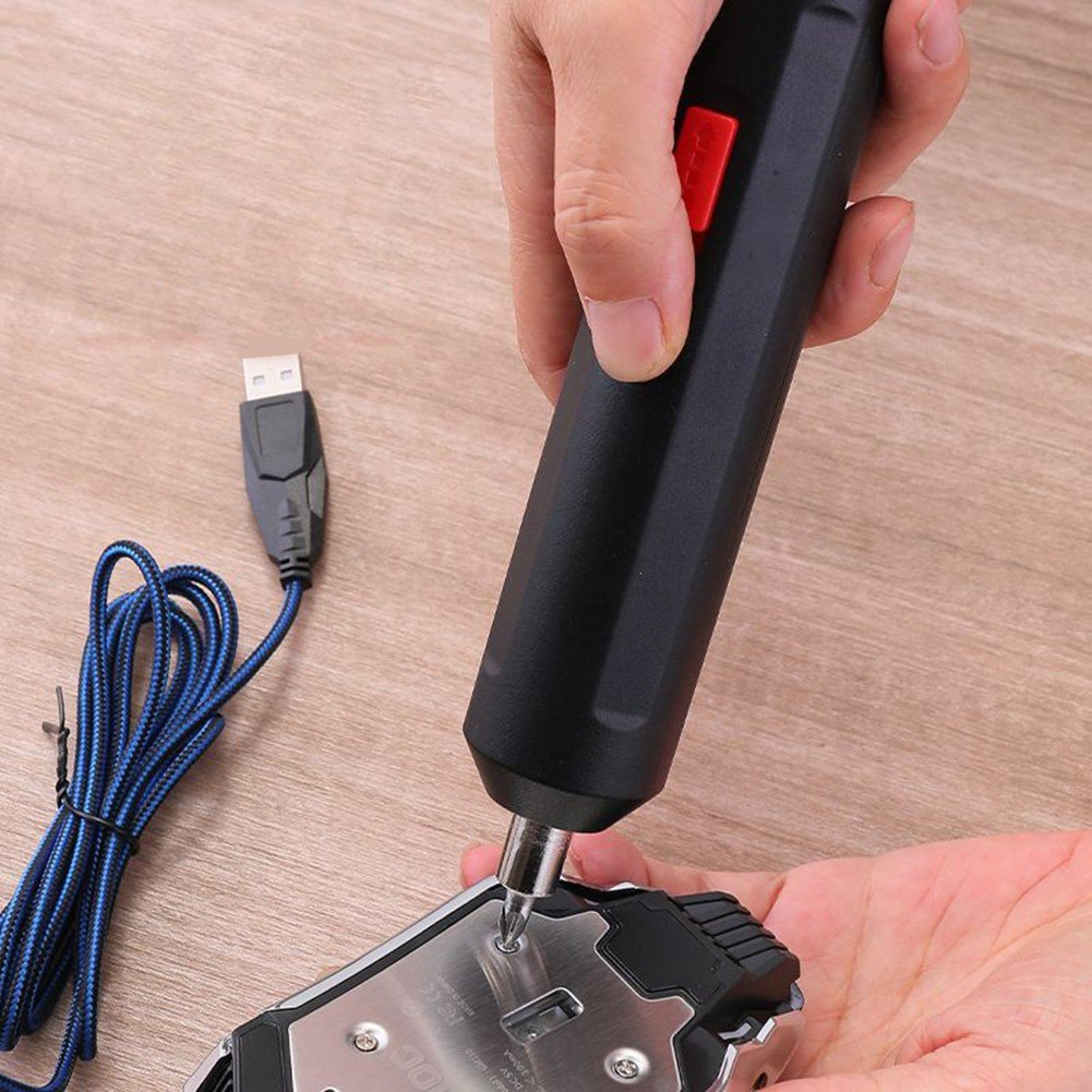 Eine Person benutzt einen schwarzen Elektroschrauber, um eine Schraube aus einer Maus zu lösen. Ein blaues USB-Kabel ist sichtbar. Der Hintergrund ist Holz.